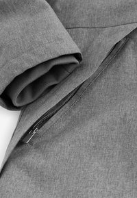 Căptușeală gri cu o textură subtilă, prezentând un detaliu cu fermoar pe un mânecă, evidențiind un tiv răsucit și o căptușeală interioară netedă.