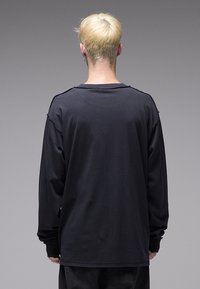 Μαύρο μακρυμάνικο πουκάμισο με άνετη εφαρμογή, στρογγυλή λαιμόκοψη και διακριτικές λεπτομέρειες ραφών. Κατασκευασμένο από απαλό βαμβακερό ύφασμα.