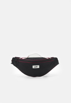 Zwarte Nike heuptas met witte en bordeaux accenten, voorvak met rits en wit handvat bovenop, weergegeven tegen een effen achtergrond.