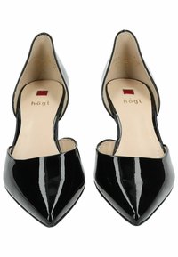 Chaussures à bout pointu en cuir verni noir avec un design découpé et une texture lisse. Elles présentent une semelle intérieure beige avec un détail de marque.