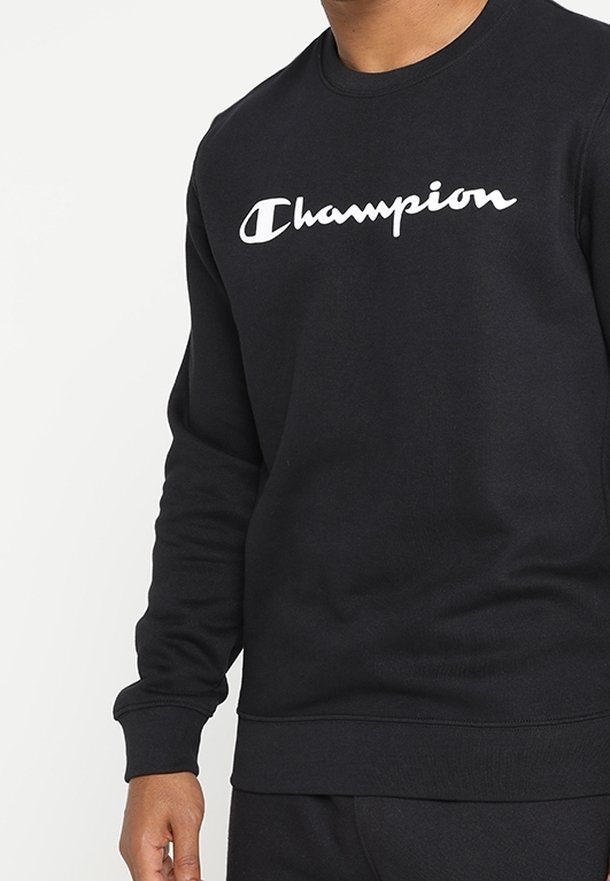 Svart sweatshirt med rund hals, tillverkad av bomullsblandat tyg. Har en vit "Champion"-logga över bröstet. Ribbad mudd och nederkant.