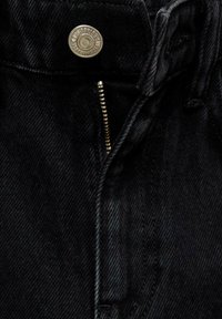 Svarta denimjeans med dragkedja och metallknäppning. Tyget har en jämn struktur med subtila blekningar och stickade detaljer.