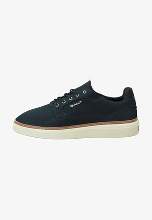Dark blue canvas sneaker with a white rubber sole, brown stitching, and logo detail on the side. Features lace-up closure and textured interior.