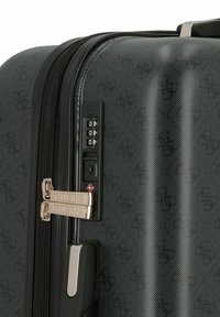 Valise rigide noire avec une finition texturée, deux zips métalliques avec un logo et un cadenas à combinaison sur le côté.