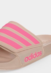Μπεζ σαγιονάρα Adidas με τρεις ροζ ρίγες στον ιμάντα και ροζ λογότυπο Adidas στο πλάι.