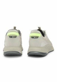 Hellgraue Sportschuhe mit einem strukturierten Obermaterial, einem reflektierenden Neonakzent an der Ferse und einer geriffelten Gummisohle.