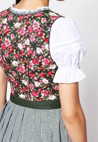 Bloemenjurk met een donkergroene lijfje met roze rozen, opstaande witte mouwen en een geruite rok met een stippen tailleband.