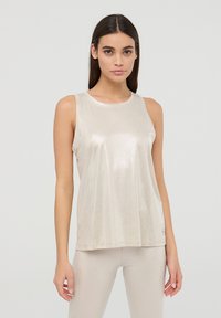 Canotta senza maniche di colore beige chiaro in un tessuto lucido e testurizzato, con collo rotondo e vestibilità ampia, abbinata a pantaloni coordinati.