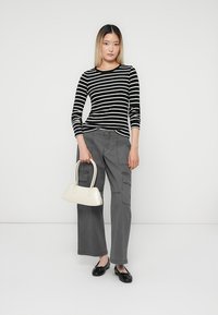 Striped black and white long-sleeve top, gray cargo pants, black flats, and a small cream handbag, set against a plain white background.