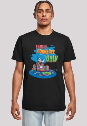 Schwarzes T-Shirt mit einem bunten Grafikdesign eines Comicfiguren in einem blauen Outfit, umgeben von Geschenkboxen und dem Text "DAS WIRD HÄSSLICH."
