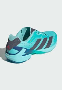 Tyrkysové sportovní boty s šedými akcenty, síťovaná svršek, texturovaný vzor, tři černé pruhy a zakřivený design paty pro podporu.