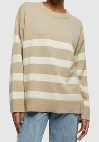 Pull beige et blanc à rayures avec un col rond, fabriqué en maille douce, présentant des épaules tombantes et des bords côtelés aux poignets et à l'ourlet.