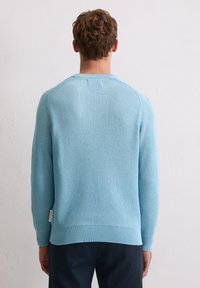 Hellblauer gestrickter Pullover mit langen Ärmeln, rundem Halsausschnitt und strukturiertem Muster, mit einem dezenten Etikett an der Seitennaht.