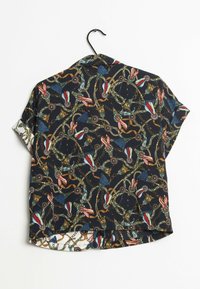 Blusa a maniche corte con sfondo scuro, caratterizzata da un motivo a catena multicolore e frange, realizzata in tessuto leggero, con orlo curvo.
