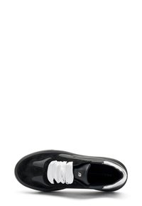 Baskets noires avec tige en daim et synthétique, lacets blancs, bout rond, accents argentés et semelle texturée. Marque sur la semelle intérieure.