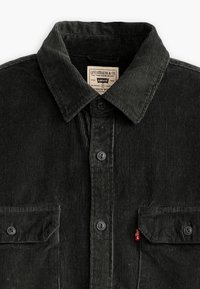 Camicia in corduroy nera con colletto, chiusura a bottoni, due tasche sul petto e un'etichetta rossa Levi's sulla tasca sinistra. Tessuto strutturato e a coste.