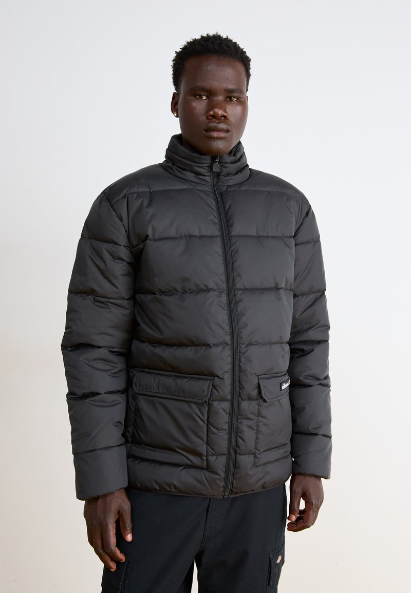 Giacca a vento nera con colletto alto, design trapuntato, chiusura con zip e due tasche anteriori. Presenta un piccolo logo sulla tasca.