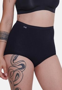 Culotte noire en coton taille haute avec une texture douce et des bordures en dentelle, comportant une petite étiquette logo sur la ceinture.