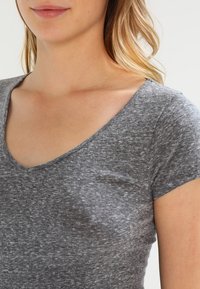 Gråmelerad T-shirt i mjuk bomull. Har V-ringning och korta ärmar, med en slät struktur och avslappnad passform.