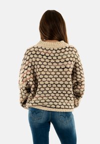 Maglione a maglia con un motivo testurizzato in crema, marrone e colori tenui. Vestibilità oversize con colletto a costine e spalle scese.