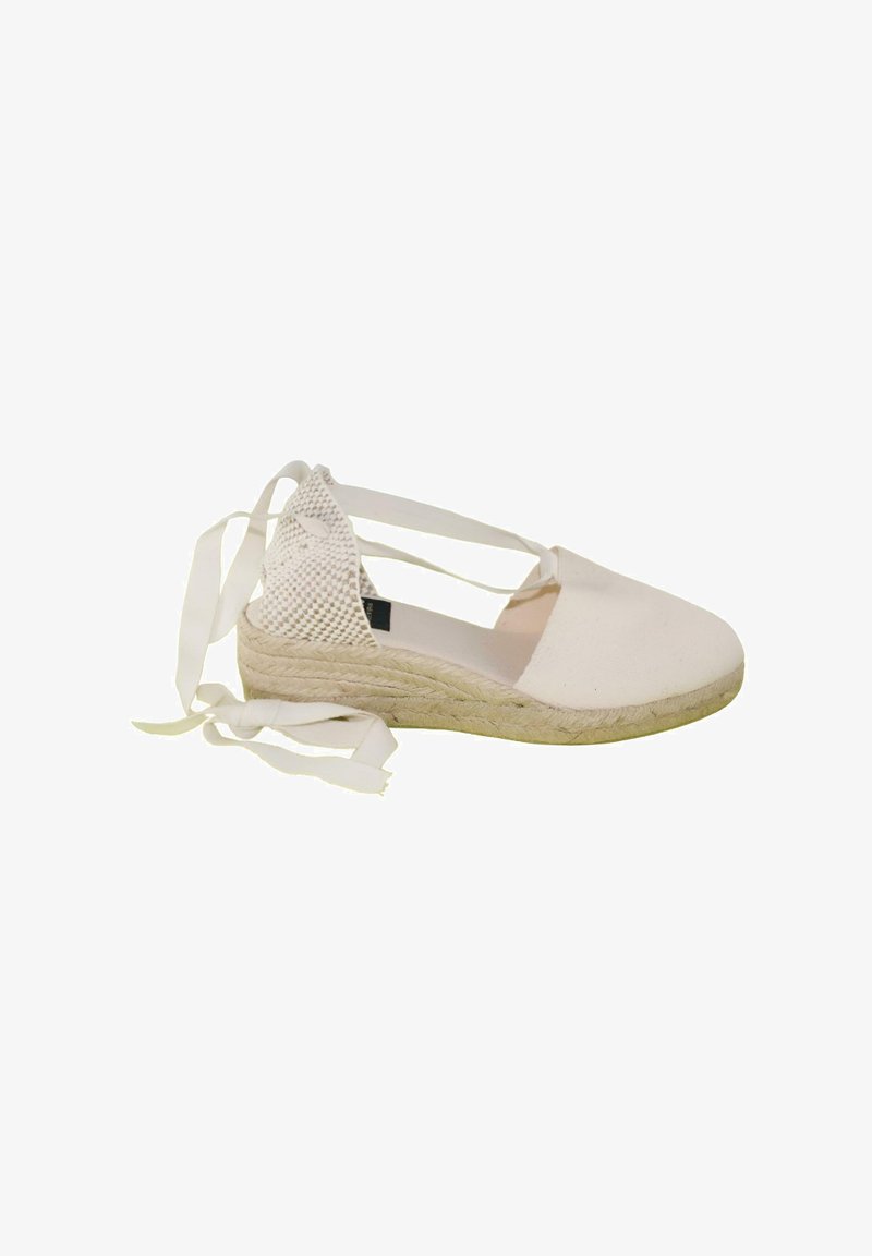 Espadrille de lona blanca con talón tejido, suela de cuña de yute y largos lazos de tela para atar al tobillo.