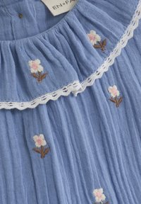 Blaues Baumwollblusenoberteil mit Falten, ausgestattet mit weißem Spitzenbesatz und floralem Stickerei in Pink und Braun. Das Etikett trägt die Aufschrift "EN+FA."