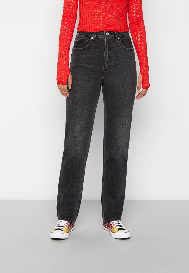 Vaqueros negros de cintura alta con diseño de pierna recta. Material de algodón. Combinados con una blusa roja con estampado y zapatillas multicolores.