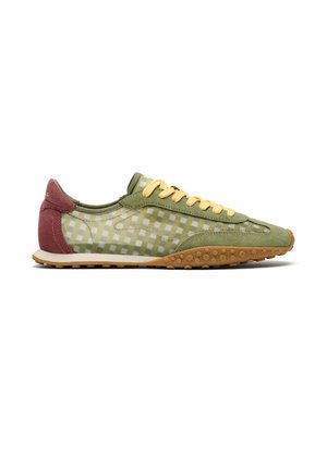 Chaussure de sport profil bas avec dessus à carreaux vert olive et beige, lacets jaunes, talon bordeaux et semelle en caoutchouc marron texturée.
