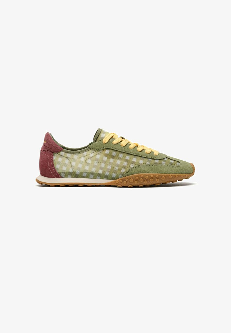 Chaussure de sport profil bas avec dessus à carreaux vert olive et beige, lacets jaunes, talon bordeaux et semelle en caoutchouc marron texturée.