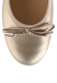 Gold leather ballet flat with a rounded toe, featuring a decorative bow and metallic accents near the front. Smooth textured finish.