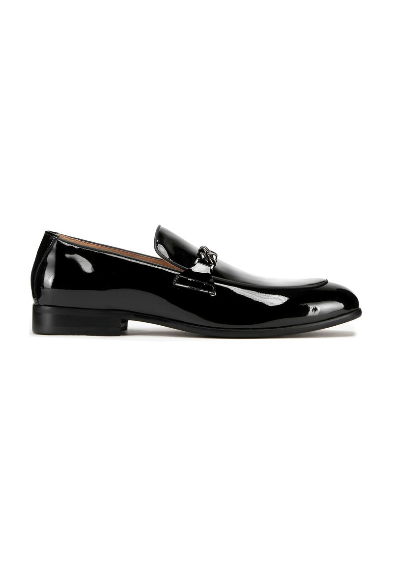 Zwarte gepatenteerde leren loafers met een gladde, glanzende afwerking, voorzien van een eenvoudige band en decoratieve hardware op de bovenkant. Lage, platte hak.