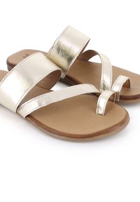 Sandalias metálicas plateadas con correas anchas y un bucle para el dedo del pie, con una suela plana marrón y una textura suave.