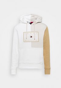 Felpa con cappuccio con blocchi di colore bianco e beige, tasca anteriore a marsupio, cordini e logo Tommy Hilfiger in oro con bandiera rossa, bianca e blu.