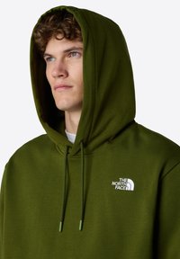 Olijfgroene hoodie met koordjes en een voorzak. Bevat een klein wit logo op de linker borst. Katoenmengsel stof, gladde textuur.