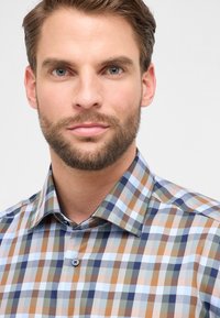 Heren geruite blouse van katoen. Kleurrijk patroon met blauwe, bruine, groene en witte vierkanten. Voorzien van een button-down kraag en knopen.
