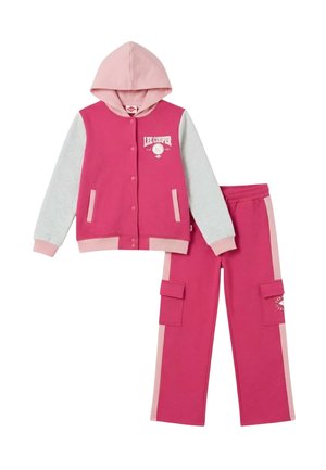 Veste à capuche rose et gris clair avec boutons-pression, associée à un pantalon cargo rose assorti avec poches latérales et bandes rose clair.