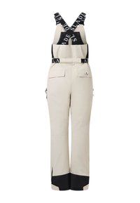 Pantalon de neige beige avec poignets noirs contrastants et bretelles noires réglables avec texte blanc. Deux poches avant à rabat et fermetures éclair latérales.