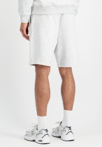 Sivé, nohavice po kolená vyrobené z jemnej, textúrovanej tkaniny, s bočnými vreckami a elastickým pásom, v kombinácii s bielymi ponožkami a teniskami.