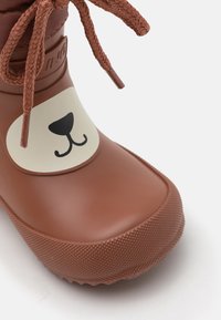 Brune gummistøvel med en glatt overflate, med et bjørneansikt-design på fronten og strukturert såle for godt grep.