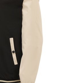 Zwarte en beige jas met een gladde textuur, voorzien van een zwarte knop en een contrasterende gestreepte elastische zoom. De mouwen zijn beige met een matte afwerking.
