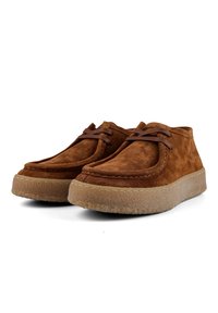 Brown suede shoes with a low profile, rounded toe, and flexible rubber sole. Features brown laces and visible stitching along the edge.