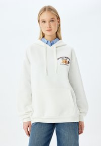 Sudadera blanca con bolsillo frontal, que presenta un diseño gráfico que incluye el texto "CUTE FRIEND TEAM" y una ilustración de un animal. Material de mezcla de algodón.