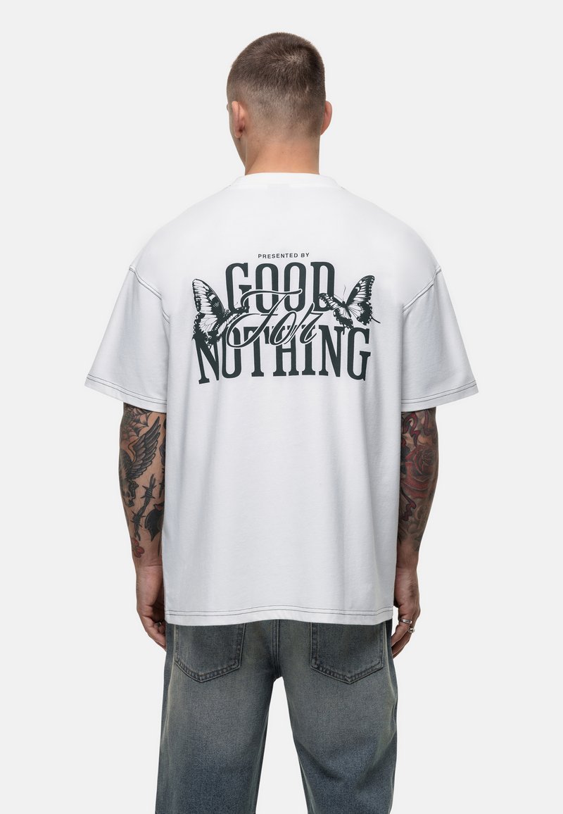 Biała, oversize koszulka z czarnym nadrukiem graficznym przedstawiającym motyle oraz tekstem "PRESENTED BY GOOD FOR NOTHING" na plecach.