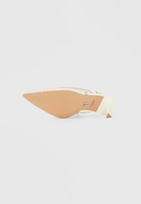 Spids tå stilet hæl i elfenbenssatin med en tekstureret nøgen sål. Fremhævet med glitrende rhinsten langs den øverste kant.