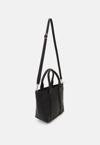 Black leather tote bag with dual top handles and a detachable shoulder strap, featuring a simple design and smooth texture.