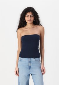 Marineblå tube-top laget av elastisk stoff, tettsittende design, glatt tekstur, uten stropper. Kombinert med lyseblå høytlivsjeans.