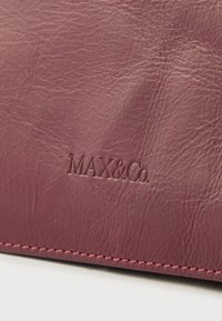 Πορτοφόλι από δέρμα μπορντό με υφή, με ανάγλυφο λογότυπο "MAX&Co." και αντίθετη ραφή κατά μήκος των άκρων.