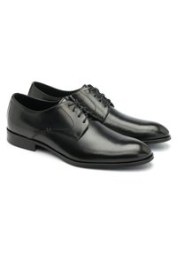 Chaussures habillées en cuir noir avec une texture lisse, bout pointu et un design classique à laçage. Elles possèdent un petit talon et des détails de couture minimalistes.