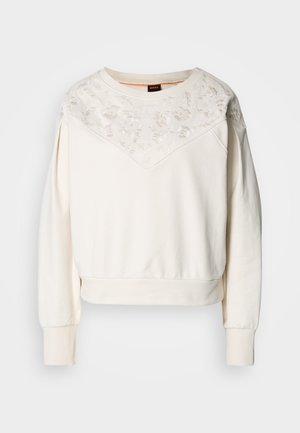 White sweatshirt with long sleeves, featuring a floral embroidered pattern at the yoke, ribbed cuffs, and a relaxed fit.
