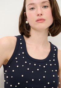 Námornická bezrukávová blůza s žebrovanou strukturou, zdobená bílými perlovými aplikacemi rozptýlenými po přední části.